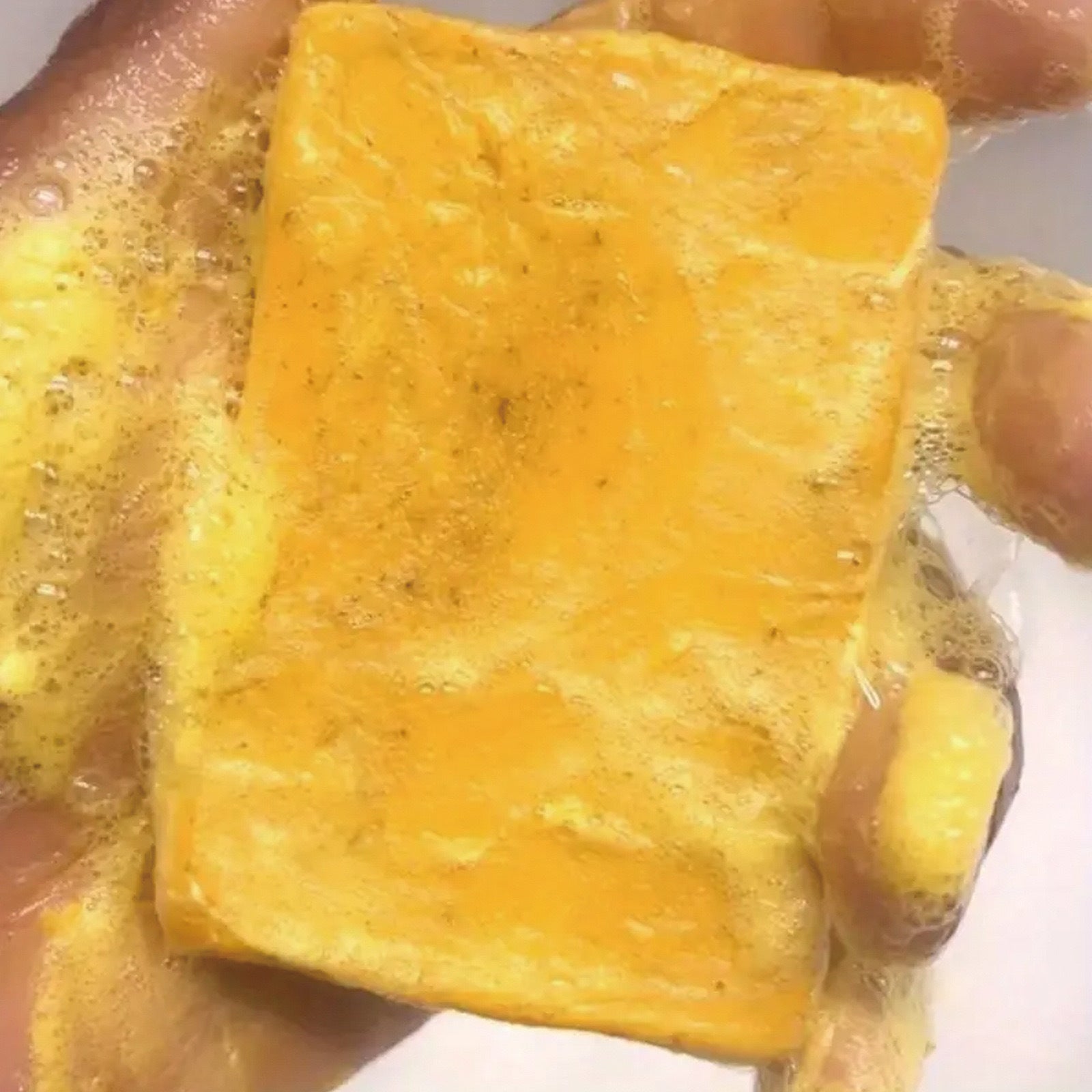 Hand holding Bella Bliss original Japanese kojic acid soap for dark spots, lathering in water